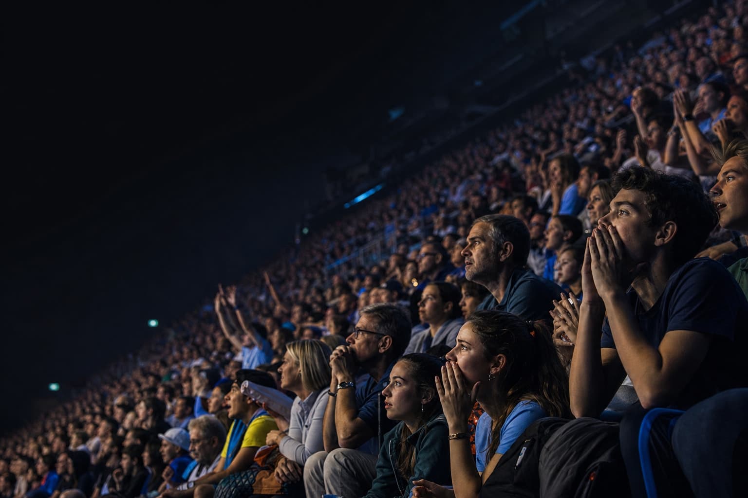 Zuschauer in der Halle — angespannte Erwartung, blaues Hallenlicht